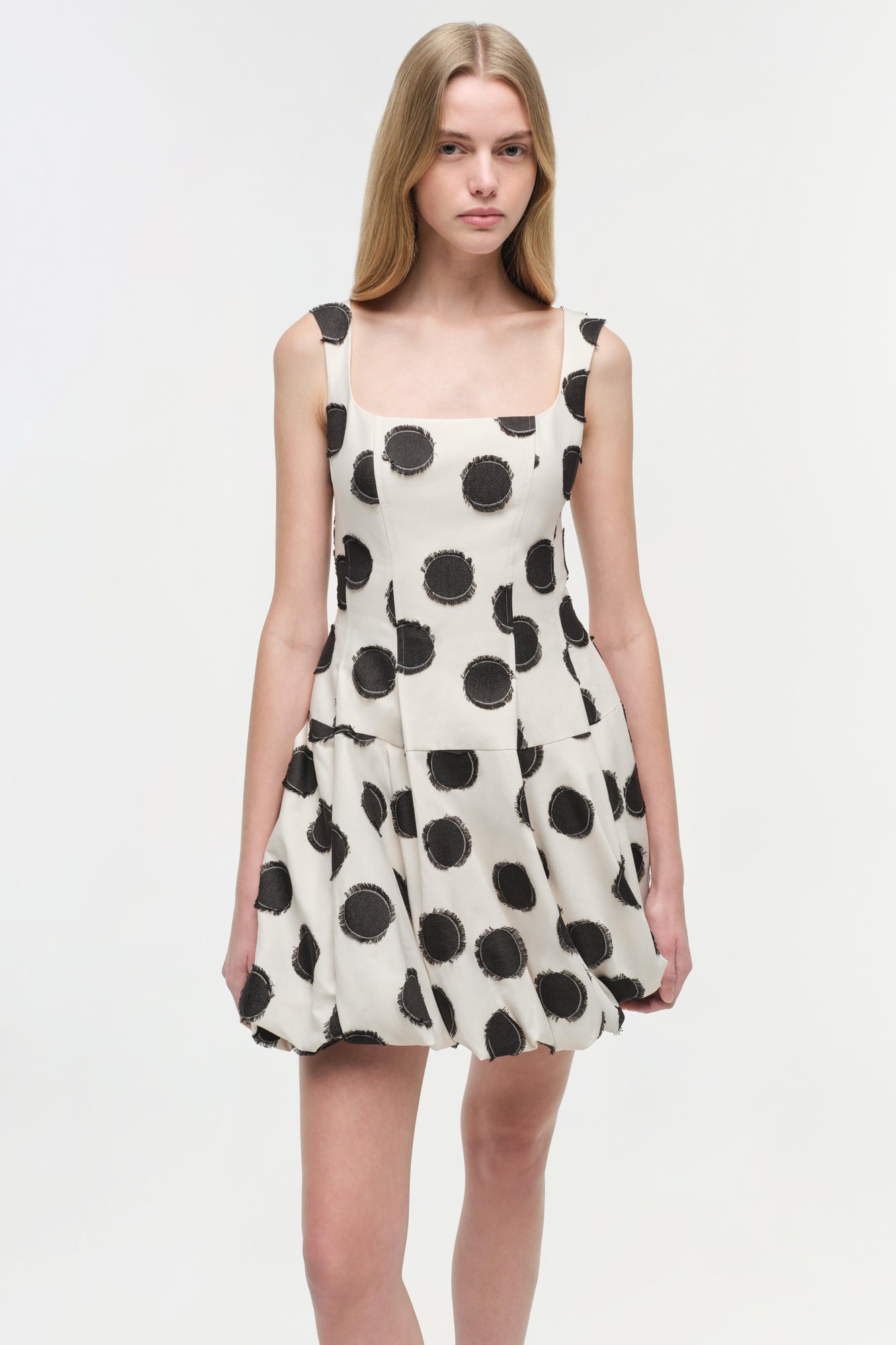 Sleeveless mini dress in cream with black circular and crescent moon print, featuring a square neckline and fit-and-flare sil