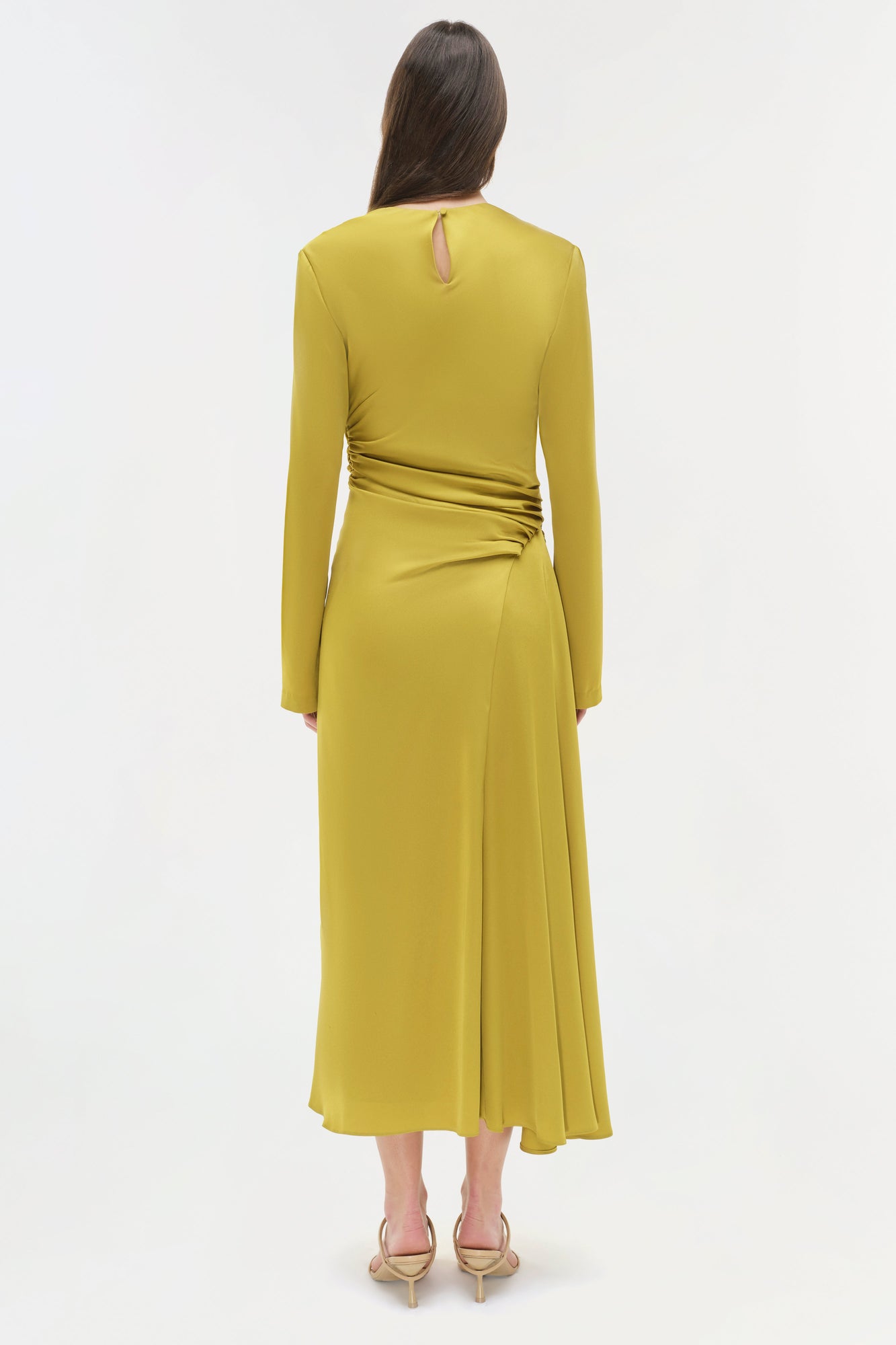 Olive-yellow satin midi dress with long sleeves, ruched side detail, and keyhole back cutout on model.