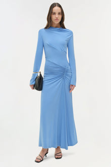 Woman wearing blue long-sleeve draped jersey midi dress with ruched side detail and black handbag.