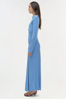 Blue draped jersey midi dress with long sleeves and ruched side detail, shown from side profile on model.