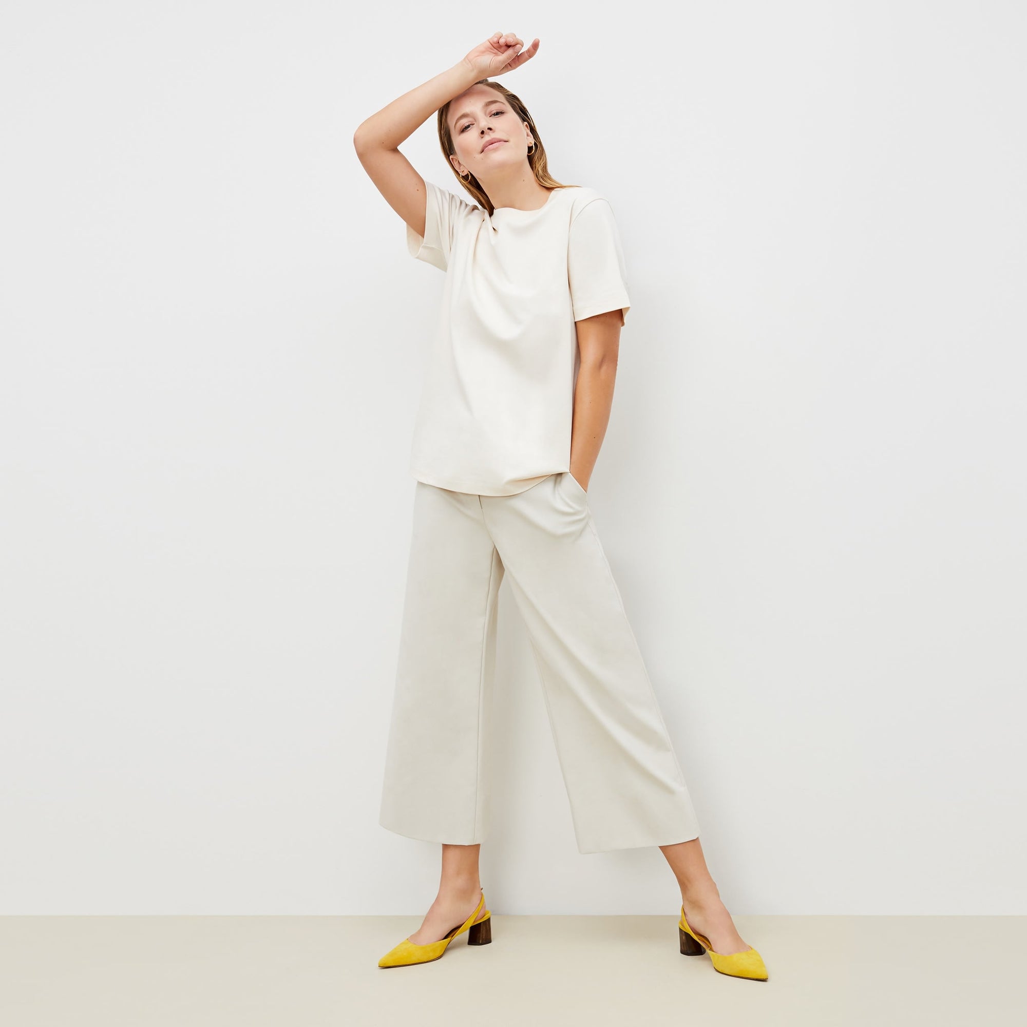 Front image of a woman standing wearing the leslie top in compact cotton in ivory | Exclude