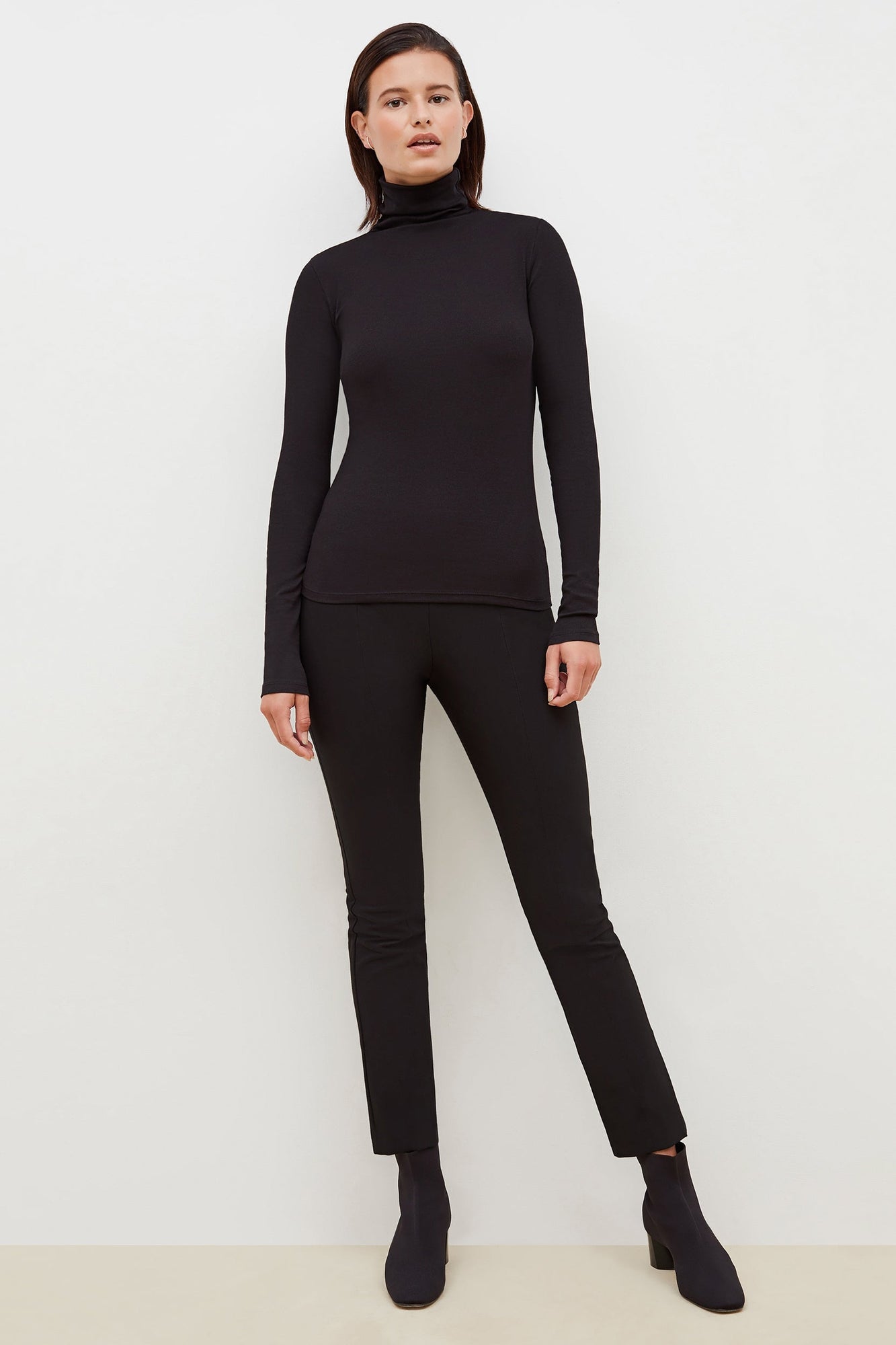 Front image of a woman standing wearing the axam top in black | Exclude