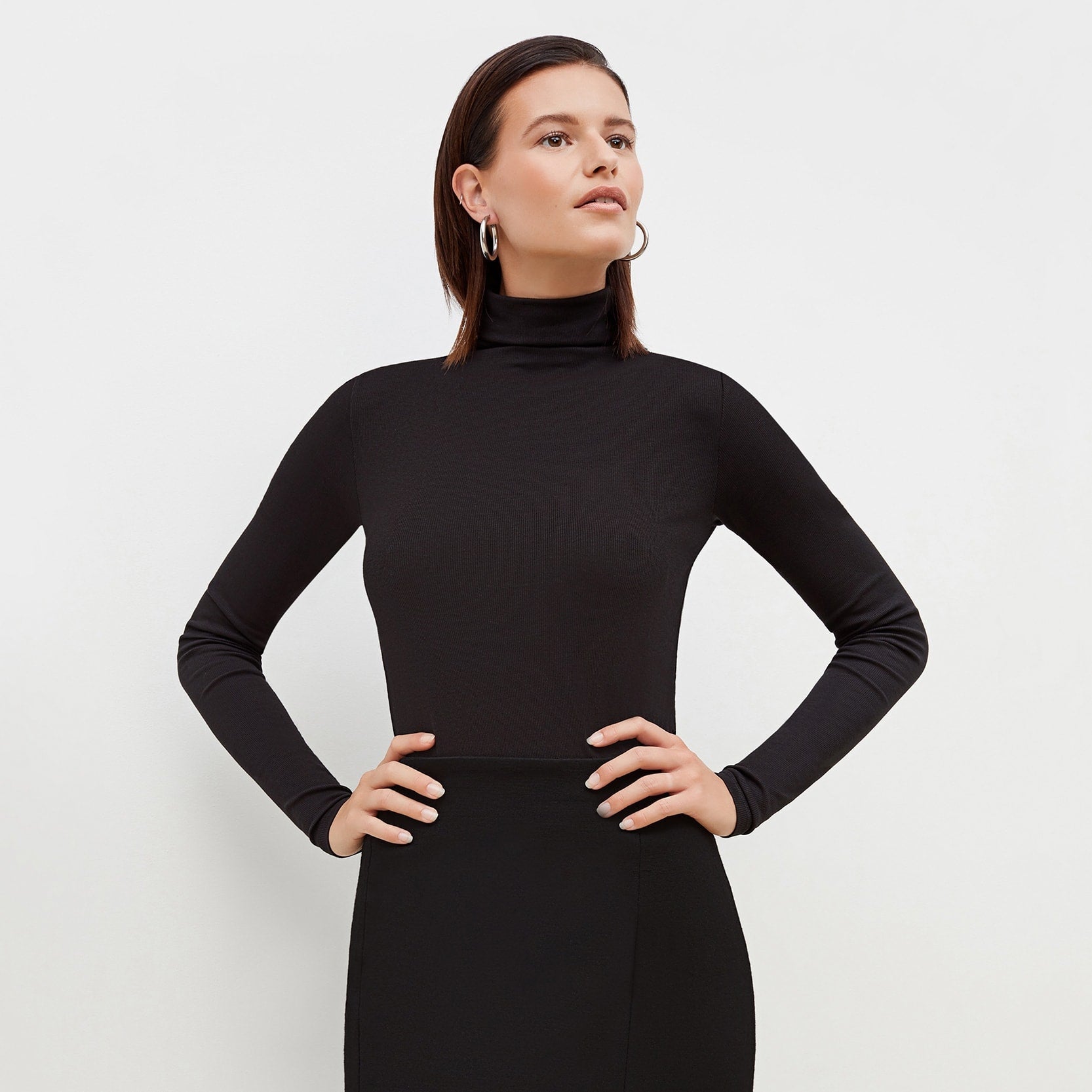 Front image of a woman standing wearing the axam top in black | Exclude