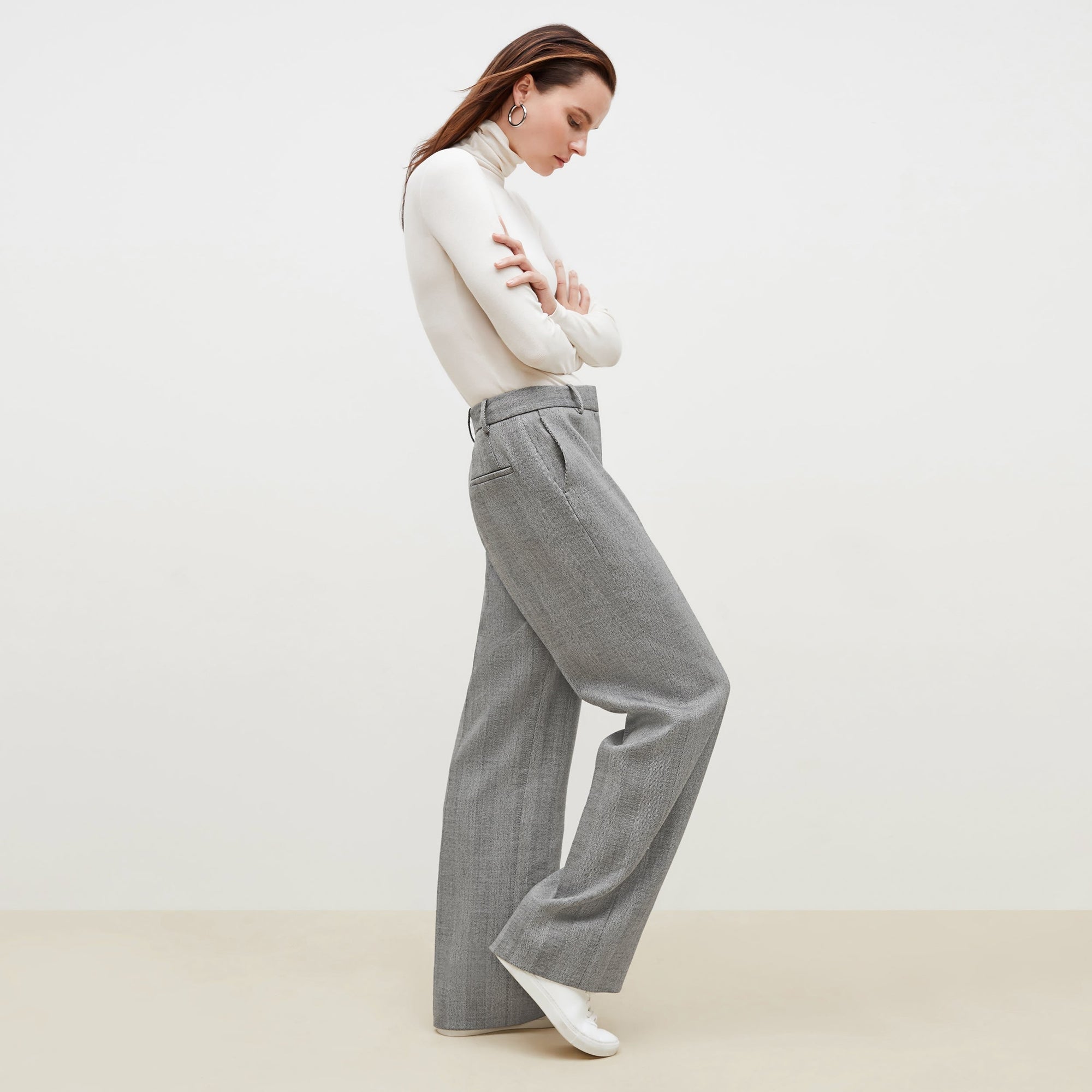 Side image of a woman standing wearing the axam top in ivory | Exclude