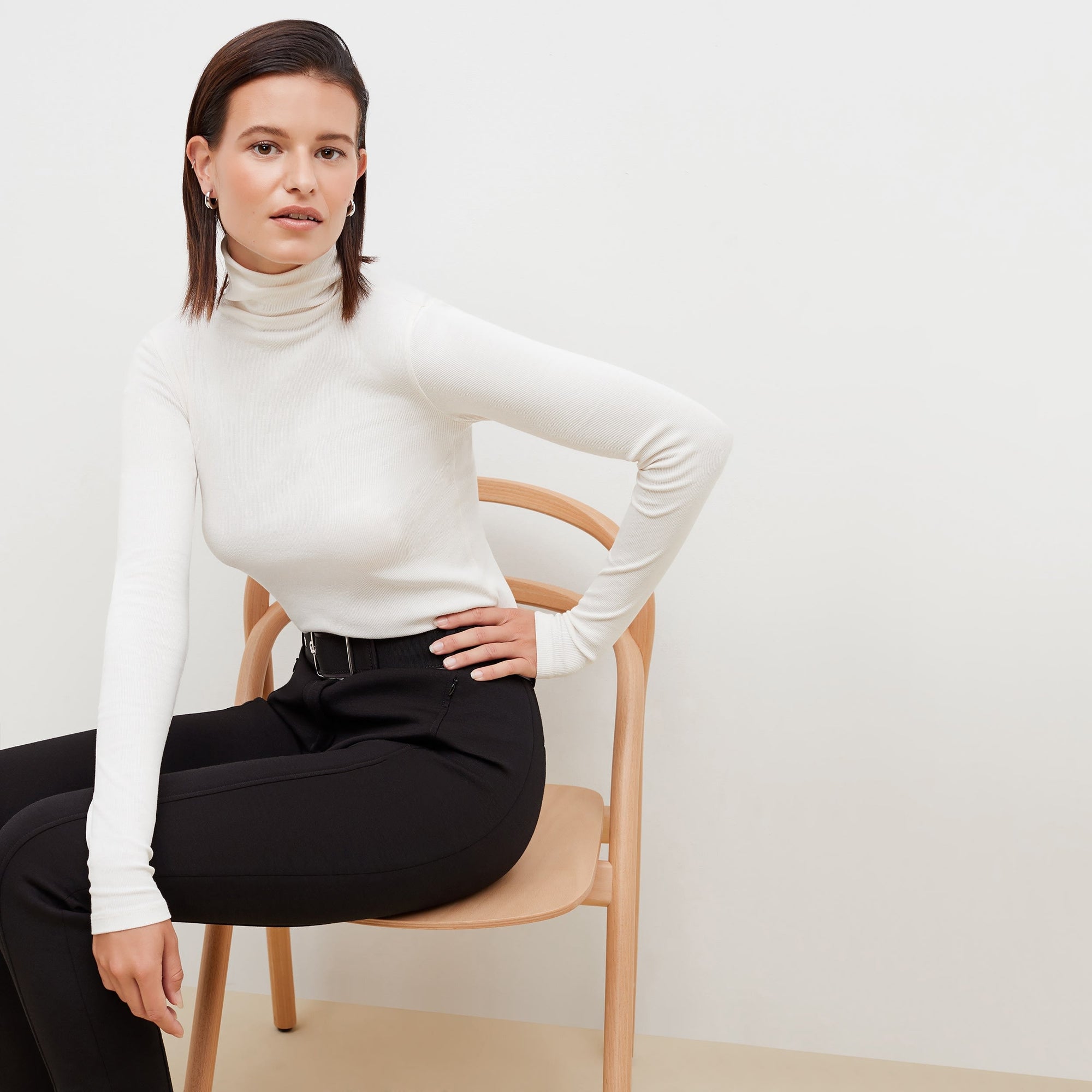 Front image of a woman standing wearing the axam top in ivory