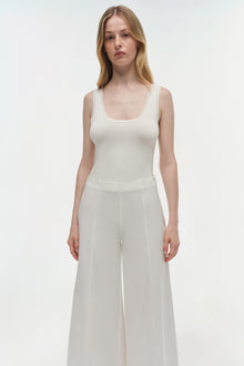 Woman wearing cream sleeveless tank top and high-waisted wide-leg cropped cotton pants in cream.