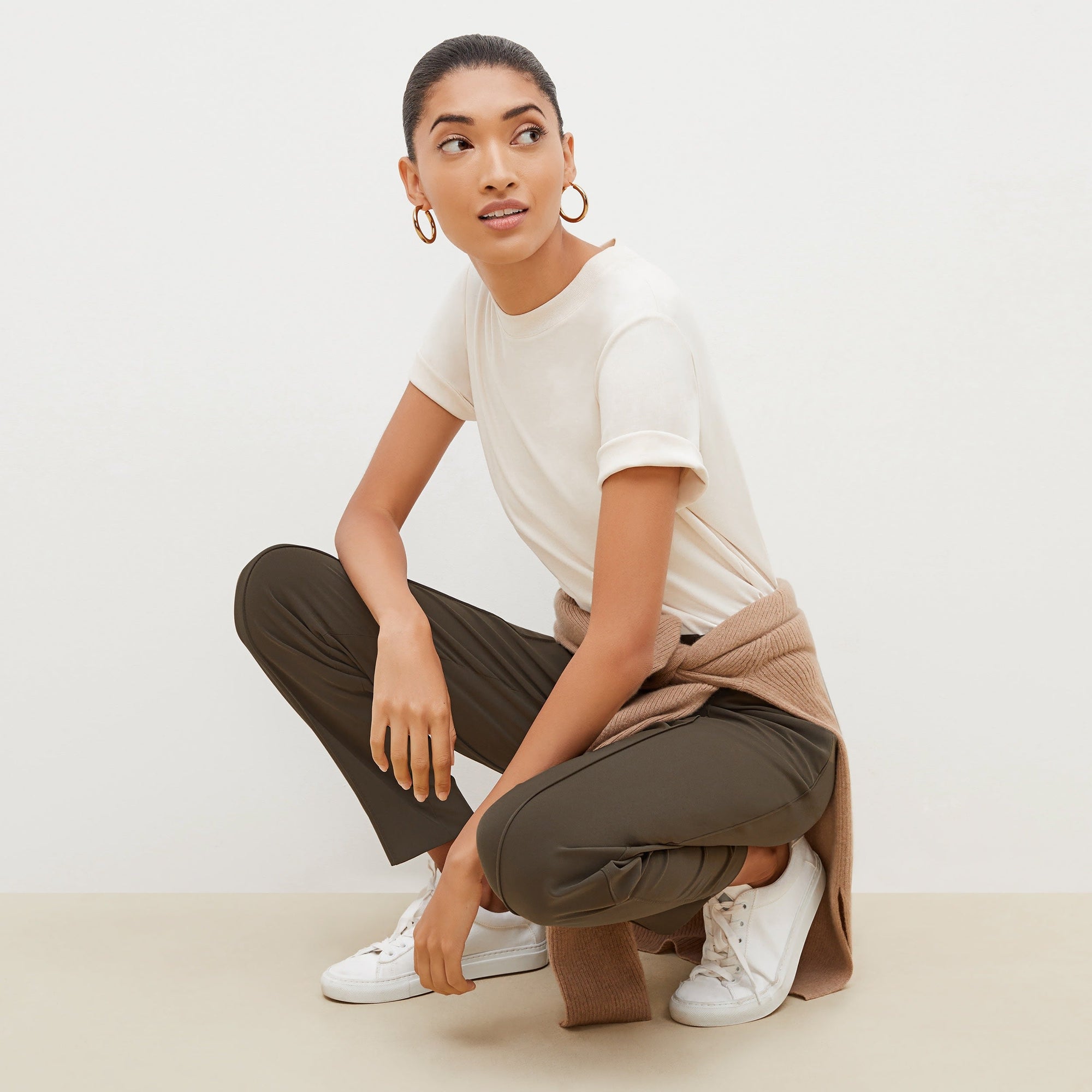 Side image of a woman standing wearing the leslie top in compact cotton in ivory | Exclude