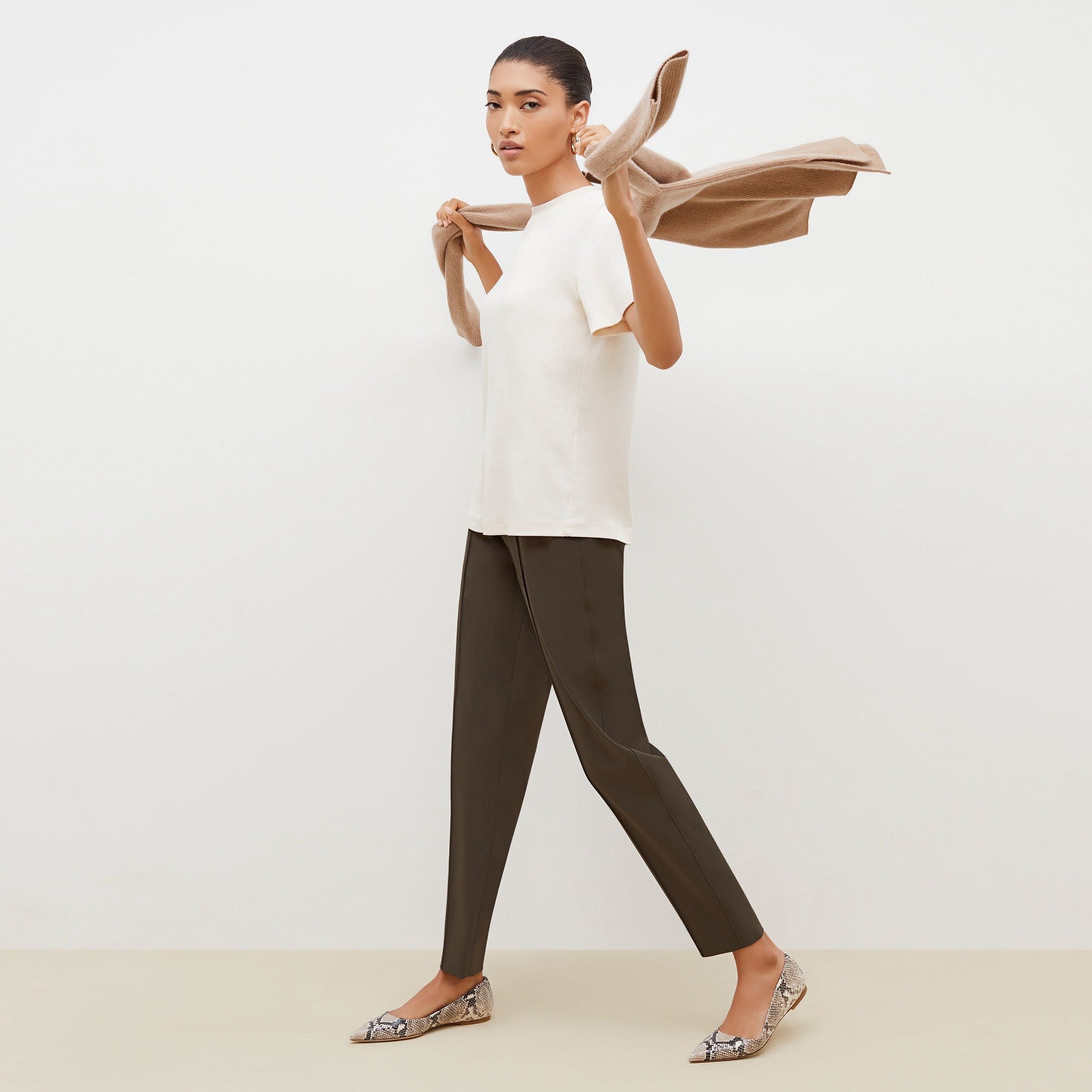 Side image of a woman standing wearing the leslie top in compact cotton in ivory | Exclude
