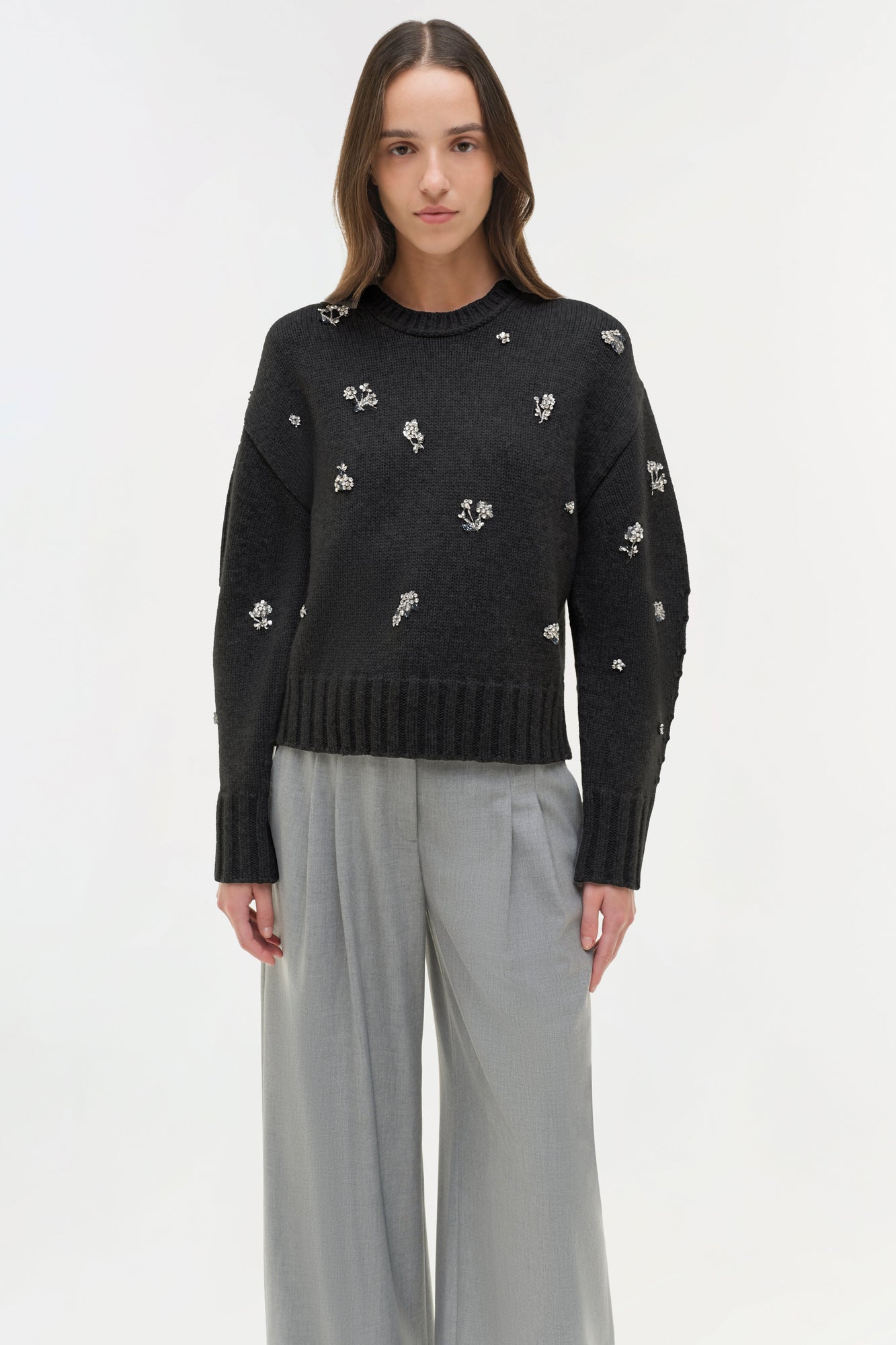 Black knit crewneck sweater with white floral embellishments scattered across the chest and sleeves.