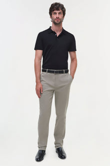 Man wearing beige cotton twill trousers with black polo shirt and dark leather shoes.