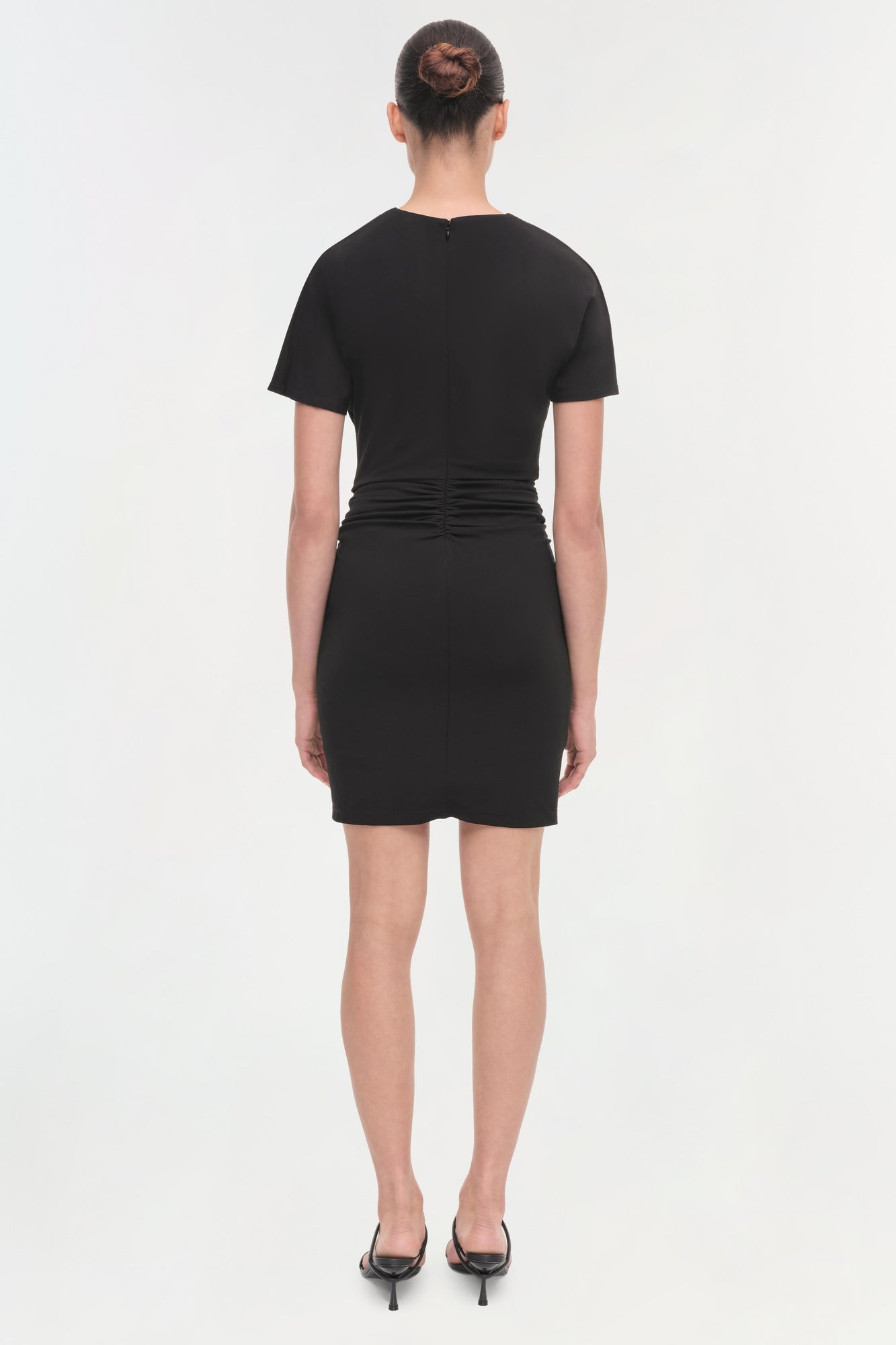 Black short-sleeved dress with ruched waist detail, shown from back view on model.