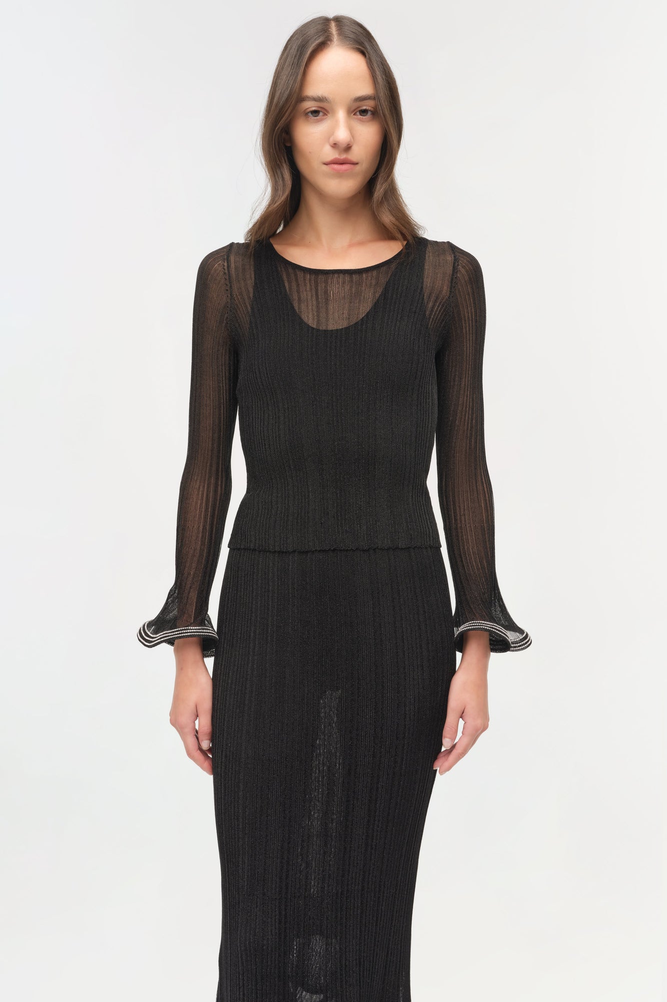 Black metallic plisse top with sheer pleated long sleeves and striped cuff details on a model.