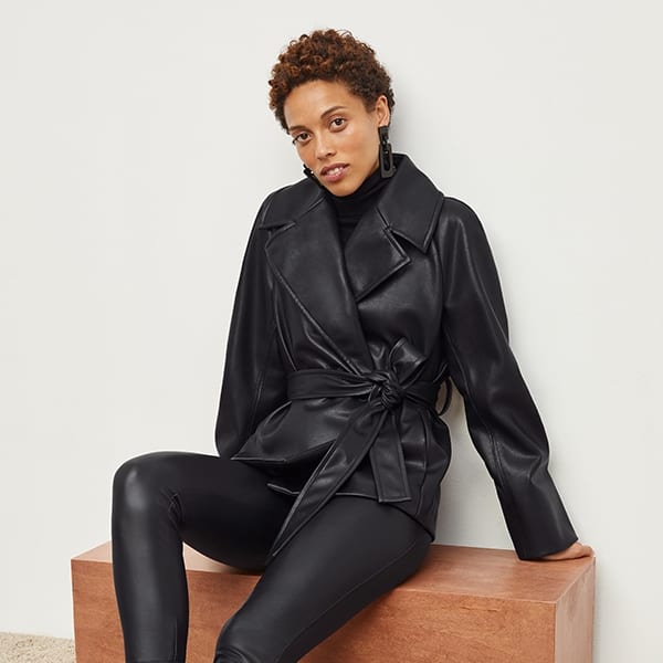 Side image of a woman standing wearing the Harrington Leather—Vegan Leather in Black | Exclude