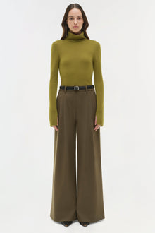 Olive wide-leg pant with pleated front waistband and black belt, styled with olive turtleneck.