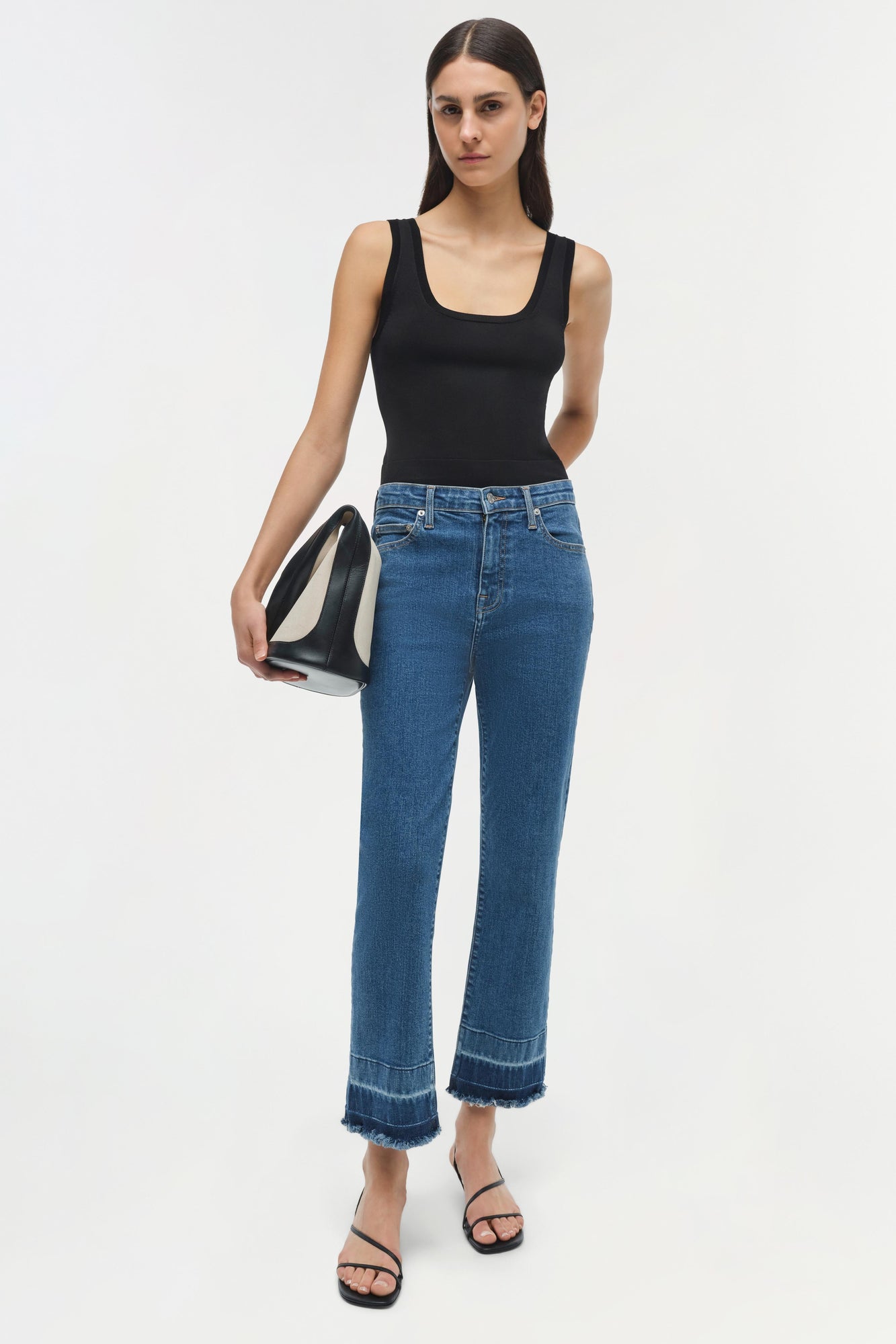 Blue straight-leg jeans with frayed hem and darker wash bands at ankles, shown with black tank top.