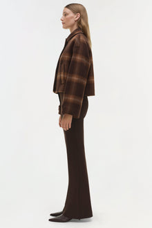 Brown plaid wool jacket with collar worn over dark trousers and black shoes.