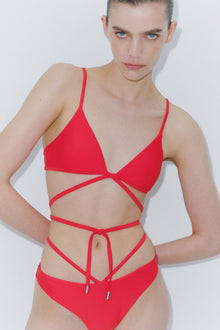 Red bikini top with thin straps and cutout details across the chest and sides.