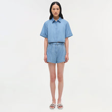 Light blue denim bishop top with short rolled sleeves and collar, worn with matching shorts.