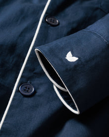 Close-up of Mens Twill Pajamas in Navy from Petite Plume, featuring luxurious, yarn-dyed cotton with white piping and black buttons. An embroidered white butterfly adorns the cuff, adding elegance and polish to the smooth fabric.
