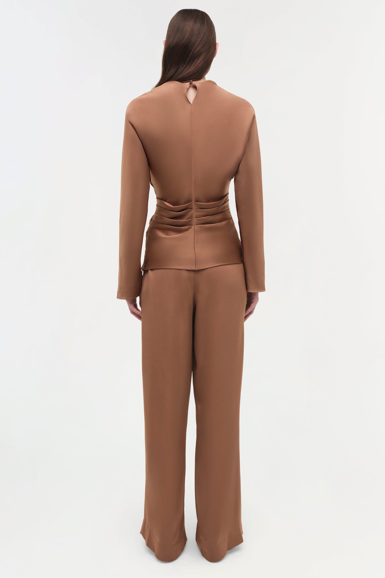 Woman wearing tan satin wide-leg pants with a matching long-sleeve cropped top, shown from back view.