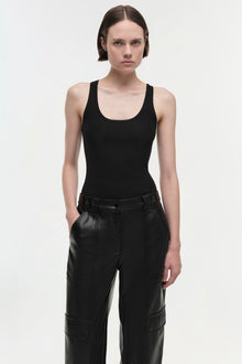 Black leather cargo pants with visible seam panels and belt loops, worn with a black ribbed tank top.