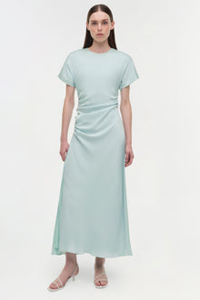 Light green satin midi dress with short sleeves and ruched detailing on the side, worn with white strappy sandals.