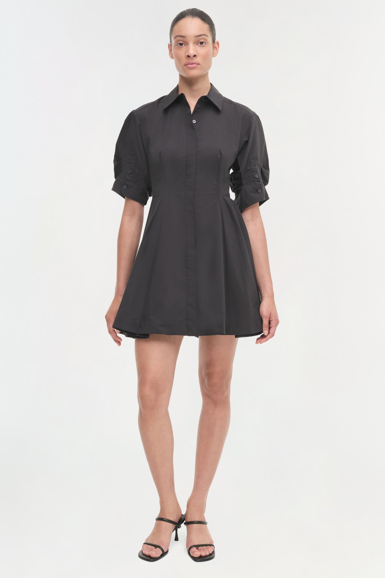 Black button-front shirt dress with rolled half sleeves, cinched waist, and A-line skirt.