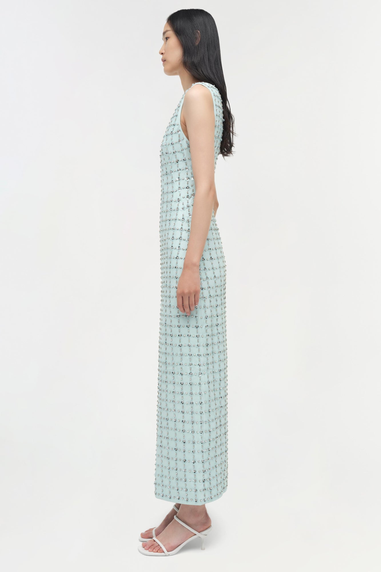 Light blue sleeveless midi dress with all-over sequin embellishments, shown on model in side profile view.