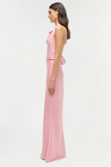 Woman wearing a pink sleeveless satin gown with a ruffled waist detail and floor-length skirt.
