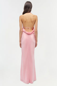 Woman wearing a pink satin gown with an open back and draped neckline, shown from behind.