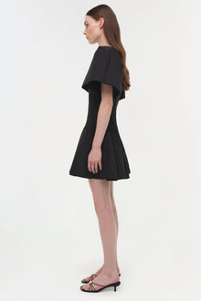 Black mini dress with layered cape sleeves and fitted bodice shown on model with black strappy heels.