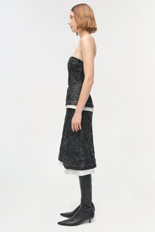 Black jacquard midi skirt with white trim, styled with a strapless top and black knee-high boots.