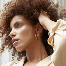 Model. Woman with curly hair wearing gold hoop earrings indoors