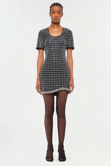 Black and white geometric patterned short-sleeve dress with beaded hem trim worn with dark tights.