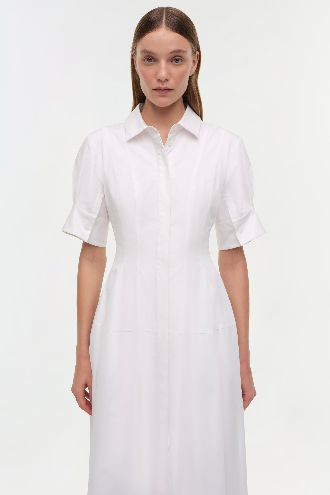 Woman wearing white cotton shirt dress with collar, button front, and short sleeves.