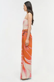 Strapless gown with ruched beige and pink bodice, orange and pink gradient skirt with abstract print, side cutout detail.