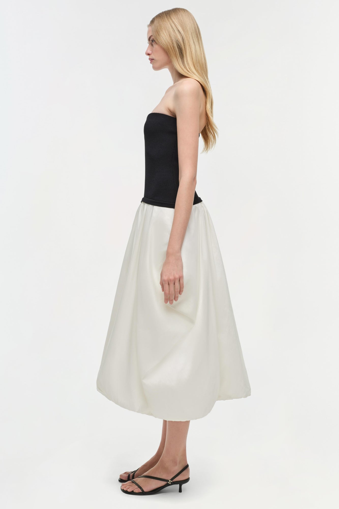 Black strapless bodice with cream taffeta midi skirt, shown on model from side profile.