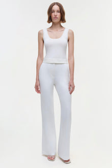 Woman wearing a white sleeveless tank top with a scoop neckline and matching white flared pants.