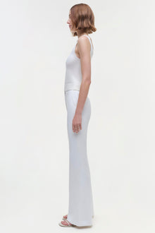 Person wearing a white sleeveless tank top with matching white wide-leg pants, shown from the side.