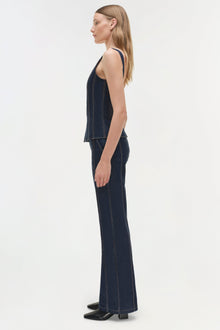 Woman wearing dark denim bustier top with contrast stitching and matching wide-leg denim pants, shown in side profile.