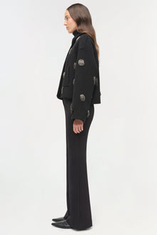Black jacket with silver beaded embellishments scattered across the front and sleeves, worn over matching black pants.