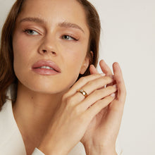 Model. Woman wearing a gold ring on a neutral background