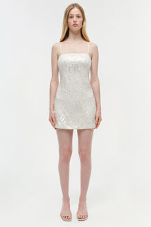 White sequined mini dress with thin straps on model wearing nude sandals.