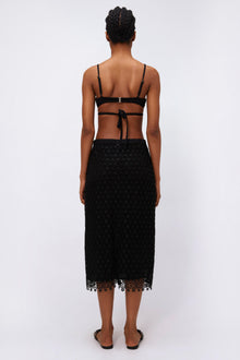Black lace midi skirt with geometric pattern and scalloped hemline, shown from back view.