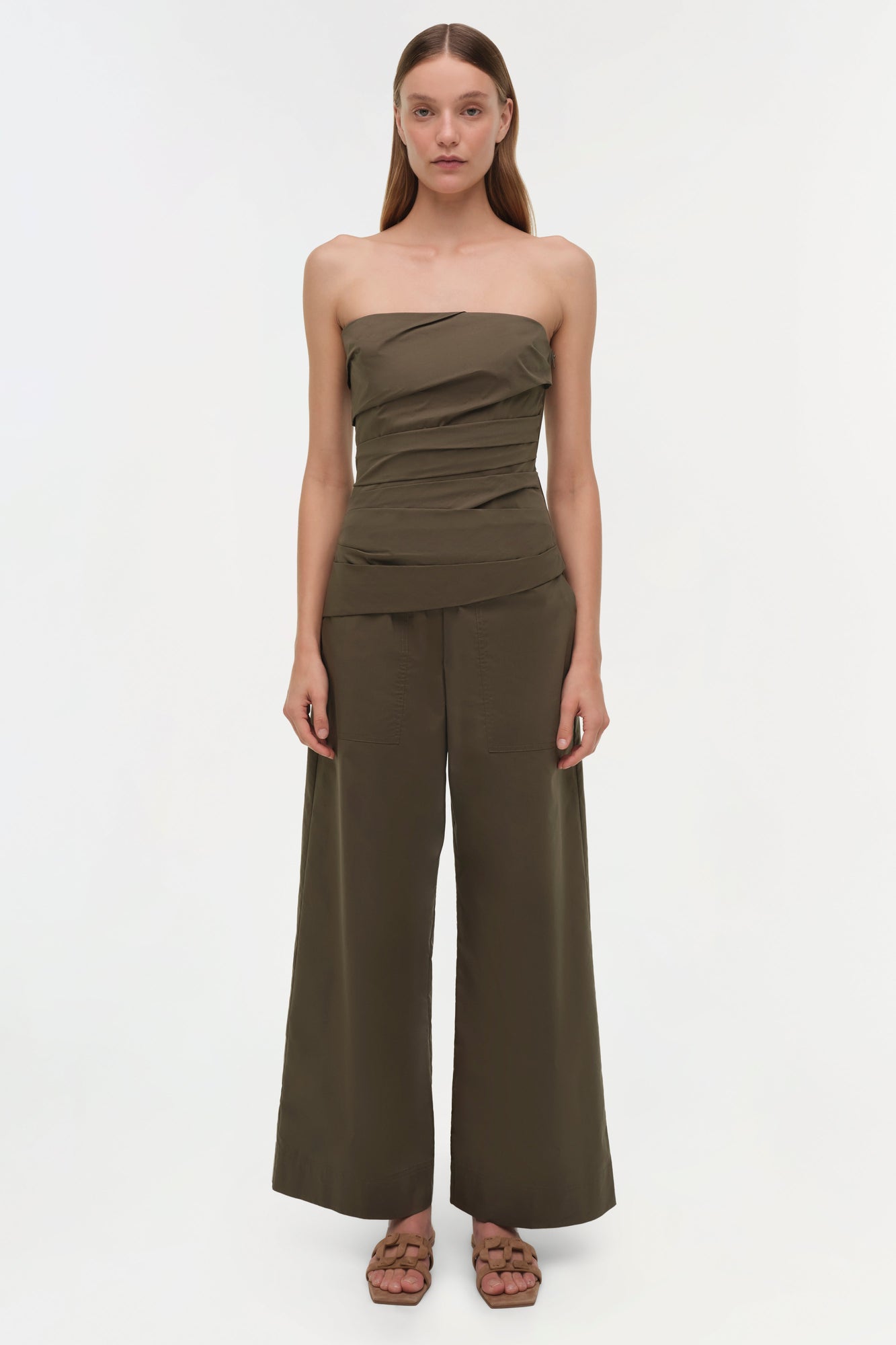 Olive green strapless bustier top with ruched detailing worn with matching wide-leg pants.