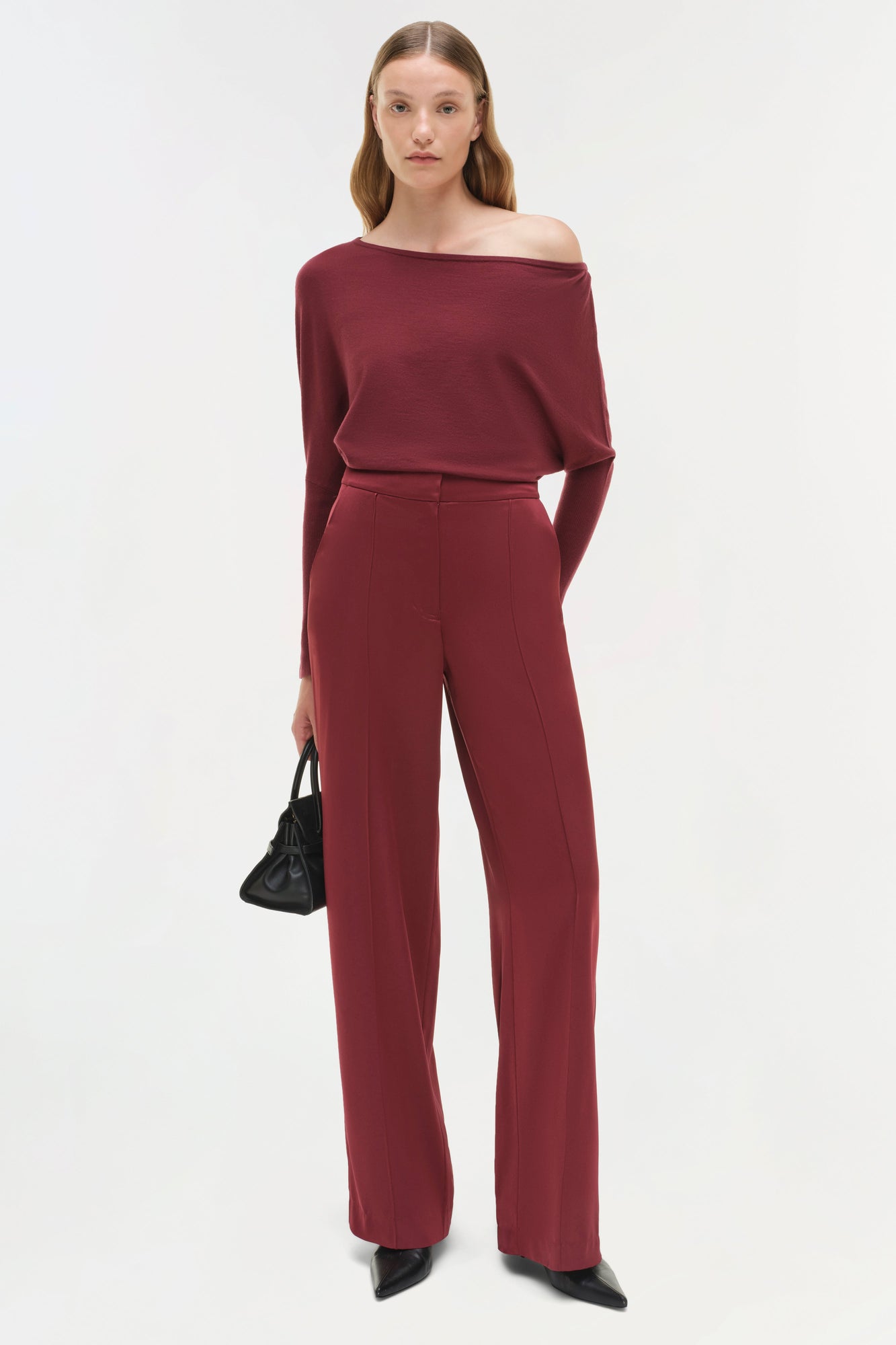 Woman wearing burgundy off-shoulder sweater with long sleeves and matching high-waisted wide-leg pants.