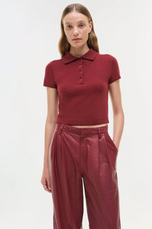 Burgundy leather wide-leg pants with high waist and pleated front detail, styled with matching knit polo shirt.