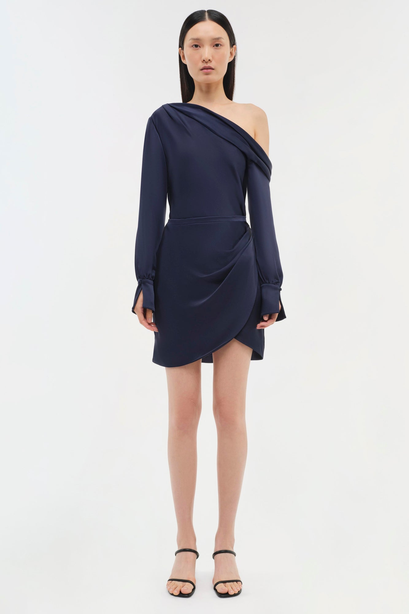 Navy blue one-shoulder dress with long sleeves and draped asymmetrical skirt detail.