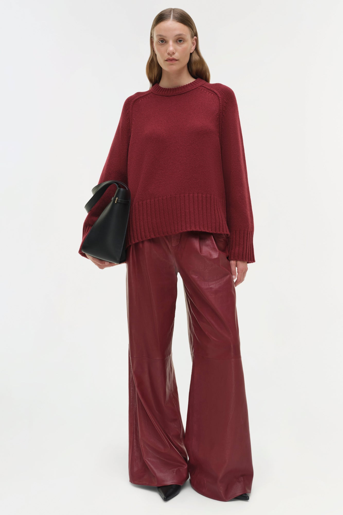 Burgundy crewneck cashmere sweater with ribbed hem and cuffs worn with matching wide-leg pants.