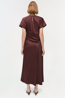Burgundy satin midi dress with short sleeves and draped side ruching detail, shown from back view.